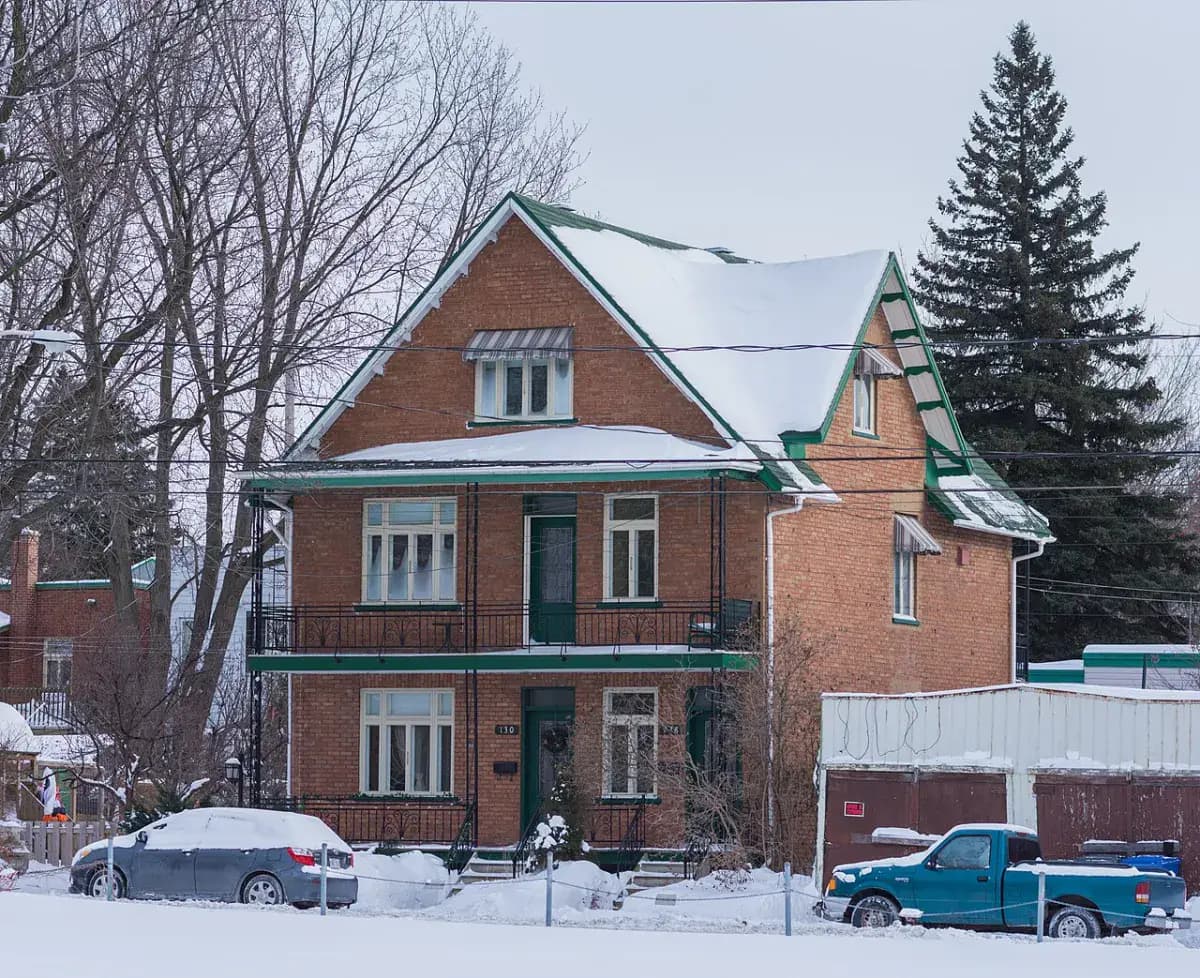Maison de brique et sapins en hiver, au Québec