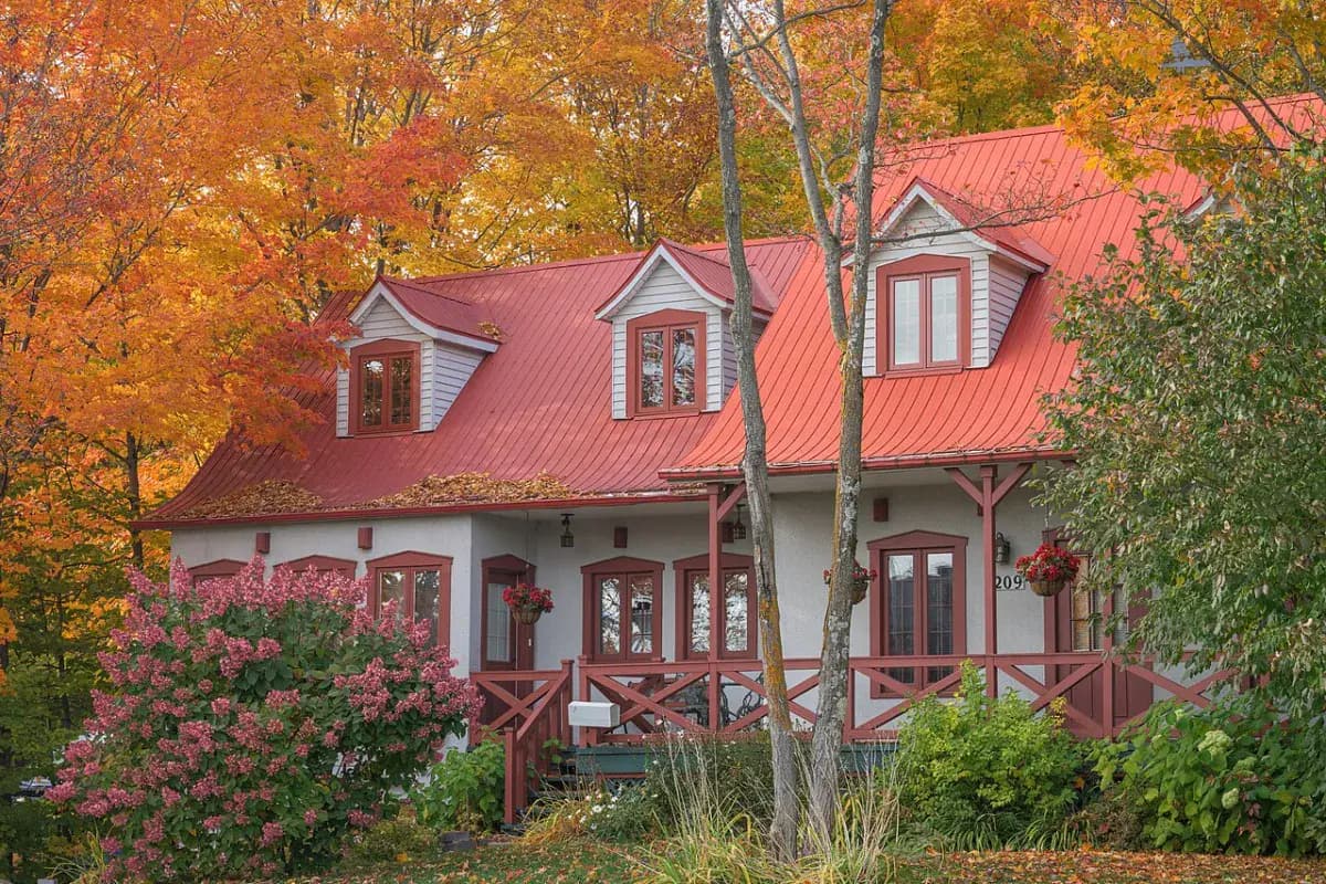 Maison à toit rouge parmi les érables en automne, au Québec